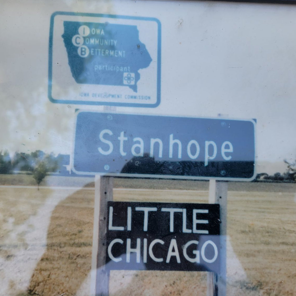 Street sign for Stanhope with a humorous description 'Little Chicago' on a rural background.