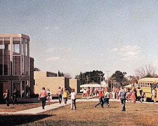 School buses and students near a building on a sunny day